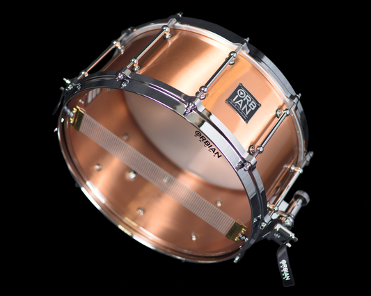A copper shell snare drum with Die Cast hoops and Dunnett Swivel throw-off, against a black background.